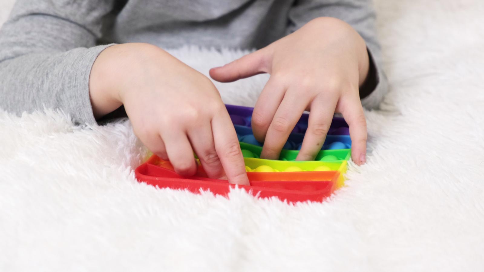 ittle-boys-hands-are-playing-an-educational-game-colorful-antistress-sensory-toy-fidget-push-pop-it-in-toddlers-hands-antistress-trendy-pop-it-toy-rainbow-sensory-fidget-new-trendy-silicone-toy